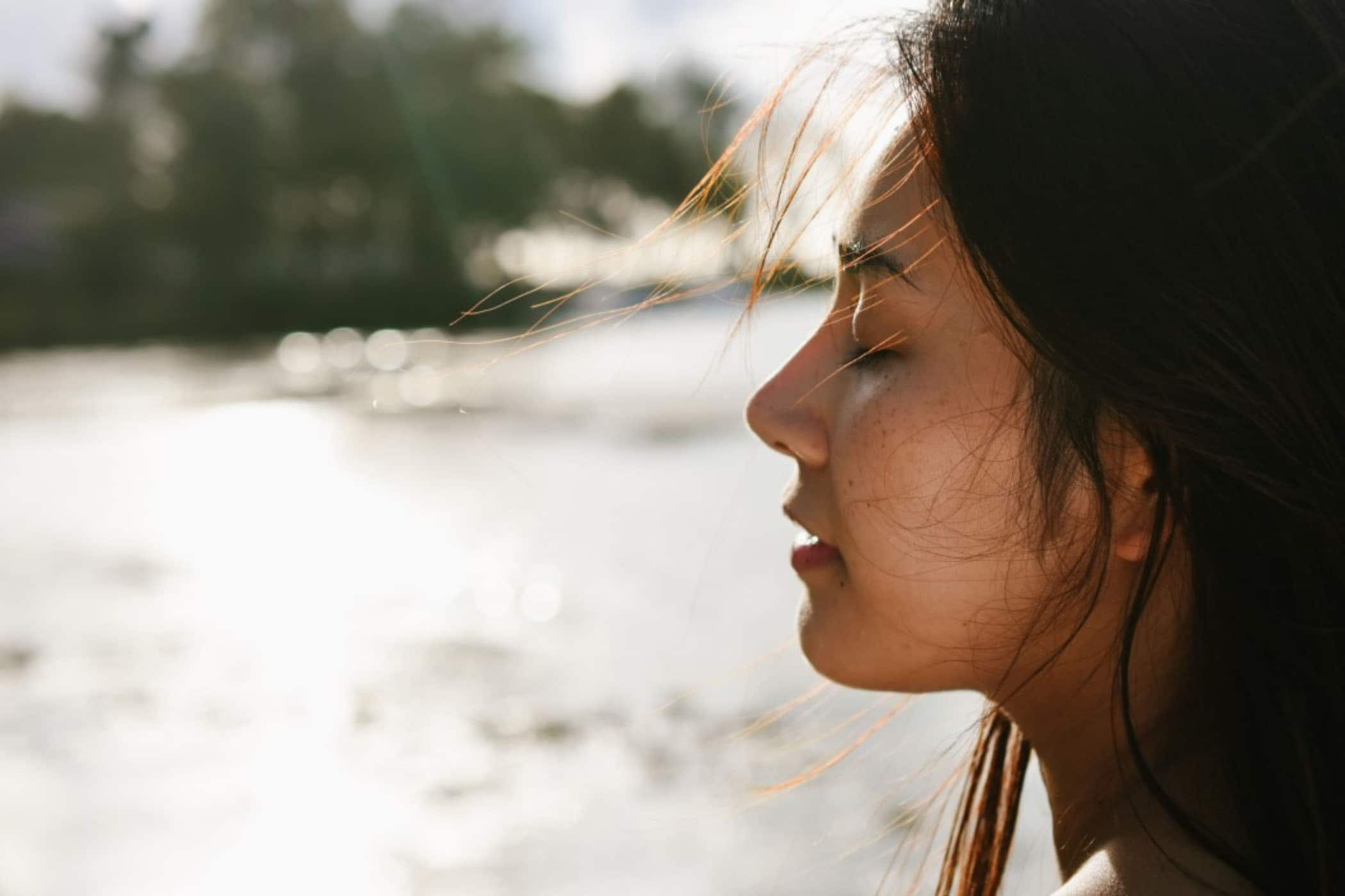 A lady with dark hair closing her eyes and meditating