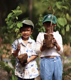 Children holding plants smiling to the camera