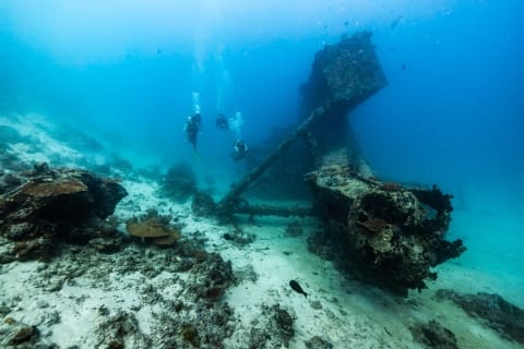 Divers exploring the Rannamaari shipwreck at Dhawa Ihuru in the Maldives