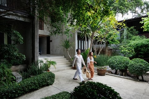 A couple walking around Homm Chura Samui, a hotel in Koh Samui, Thailand, with green plants all over the property