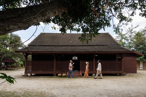 A guide showing a couple around the Coconut Museum, a centuries-old building with Thai and Chinese architecture, at Baan Boran, Koh Samui, Thailand